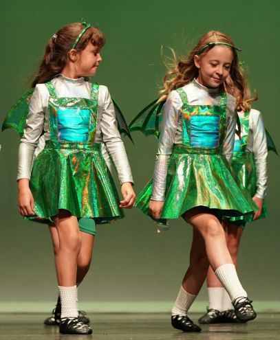 Young irish dancers on stage smiling while they dance.